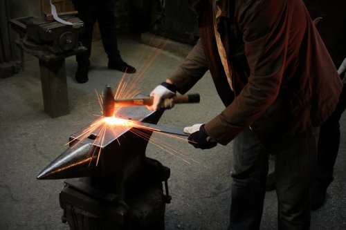 Photo of blacksmith hitting hot metal on an anvil
